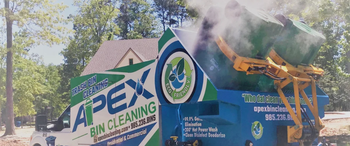 An Apex Bin Cleaning truck with two green bins being lifted by a mechanism, steam rising as they are cleaned.