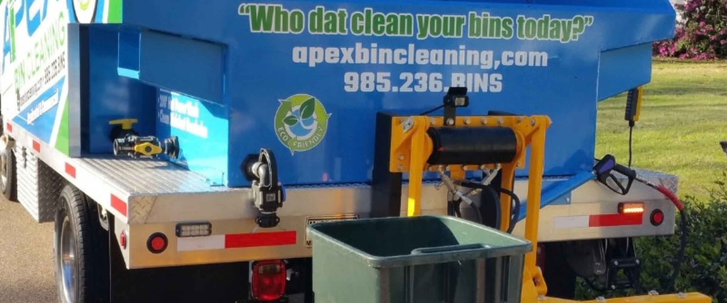 Rear view of a blue bin cleaning truck with 'Who dat clean your bins today?' text and an eco-friendly logo. Rear view of a blue bin cleaning truck with 'Who dat clean your bins today?' text and an eco-friendly logo.