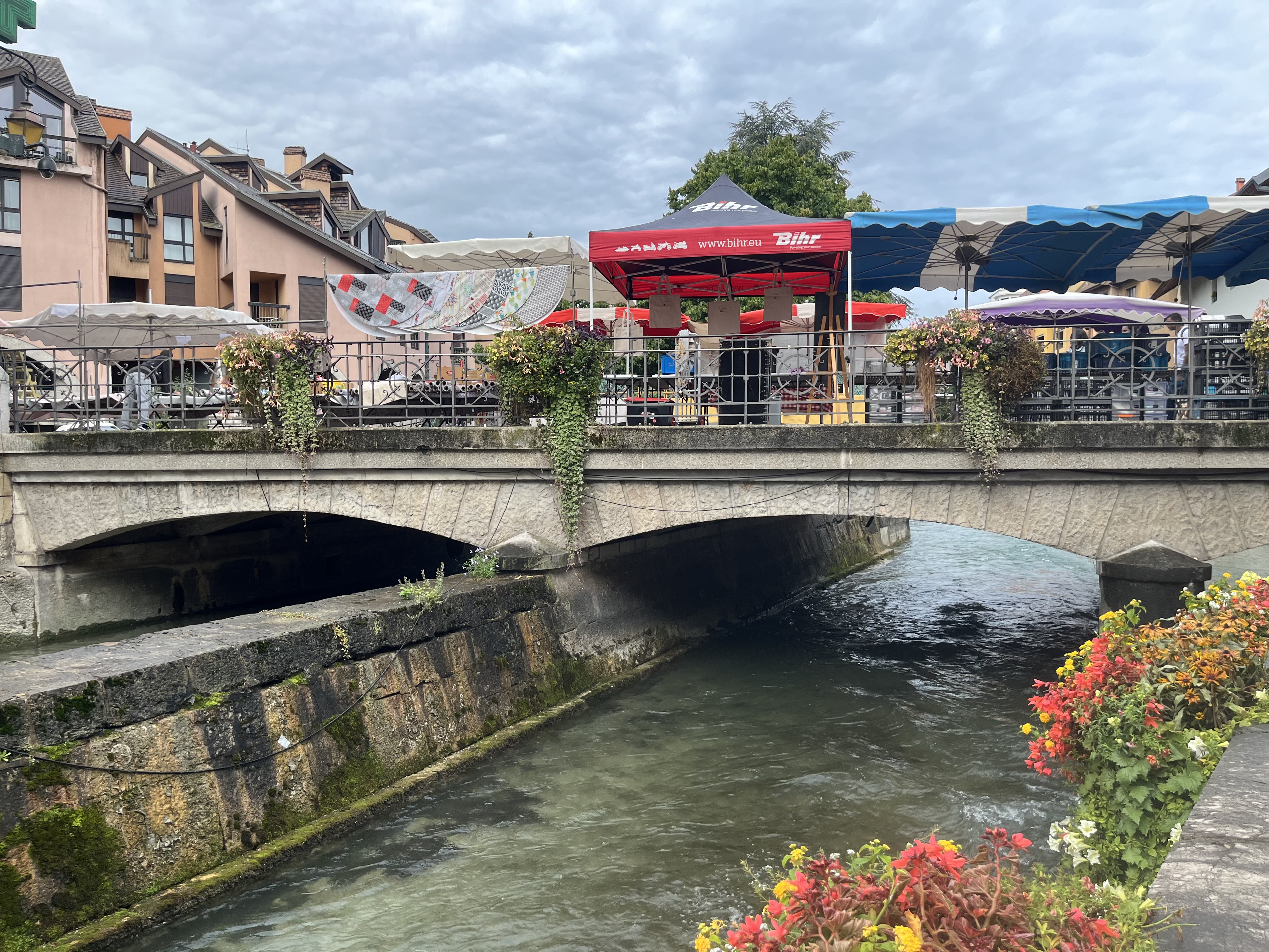Bridge over the Annecy canal with market stalls crowding the banks