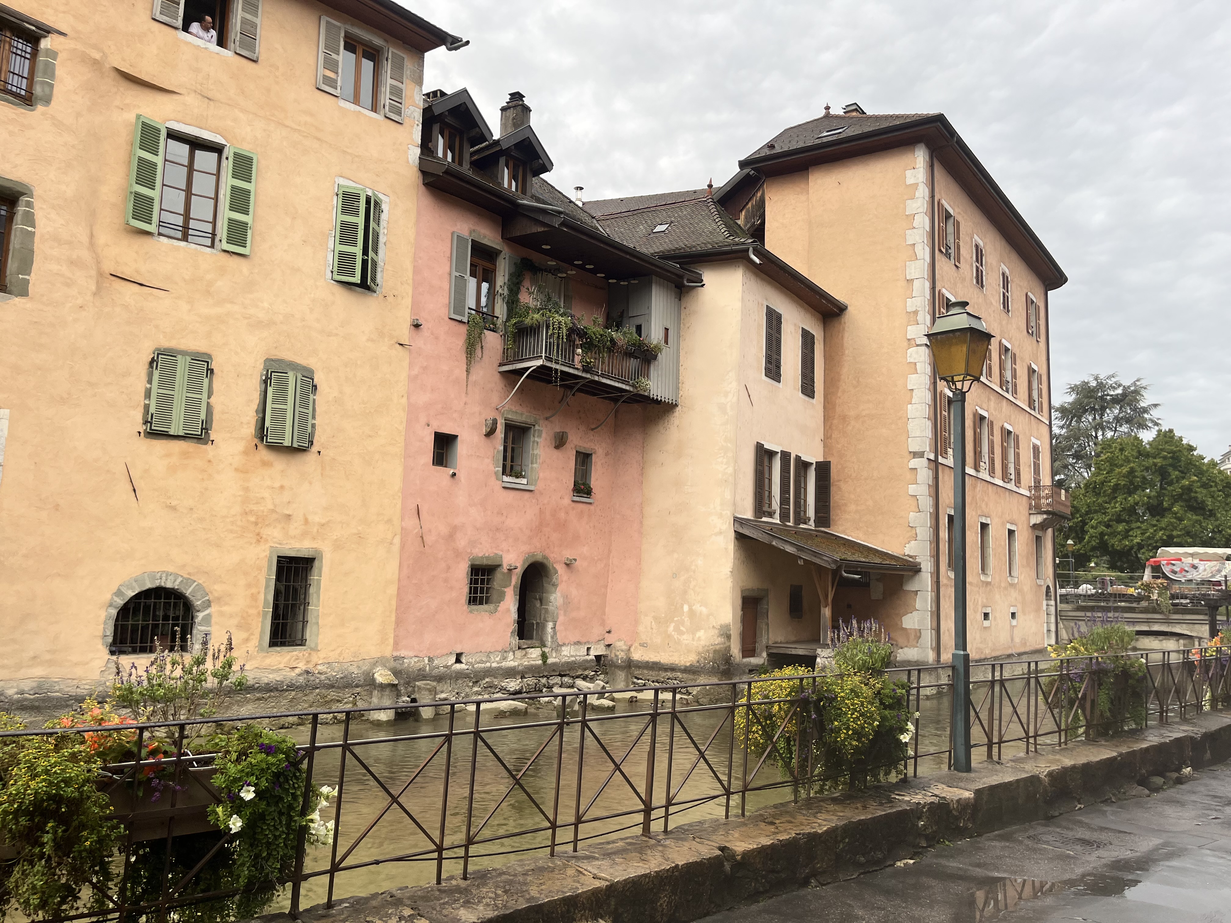 Pink and yellow buildings along the Annecy canal with reflections in the water