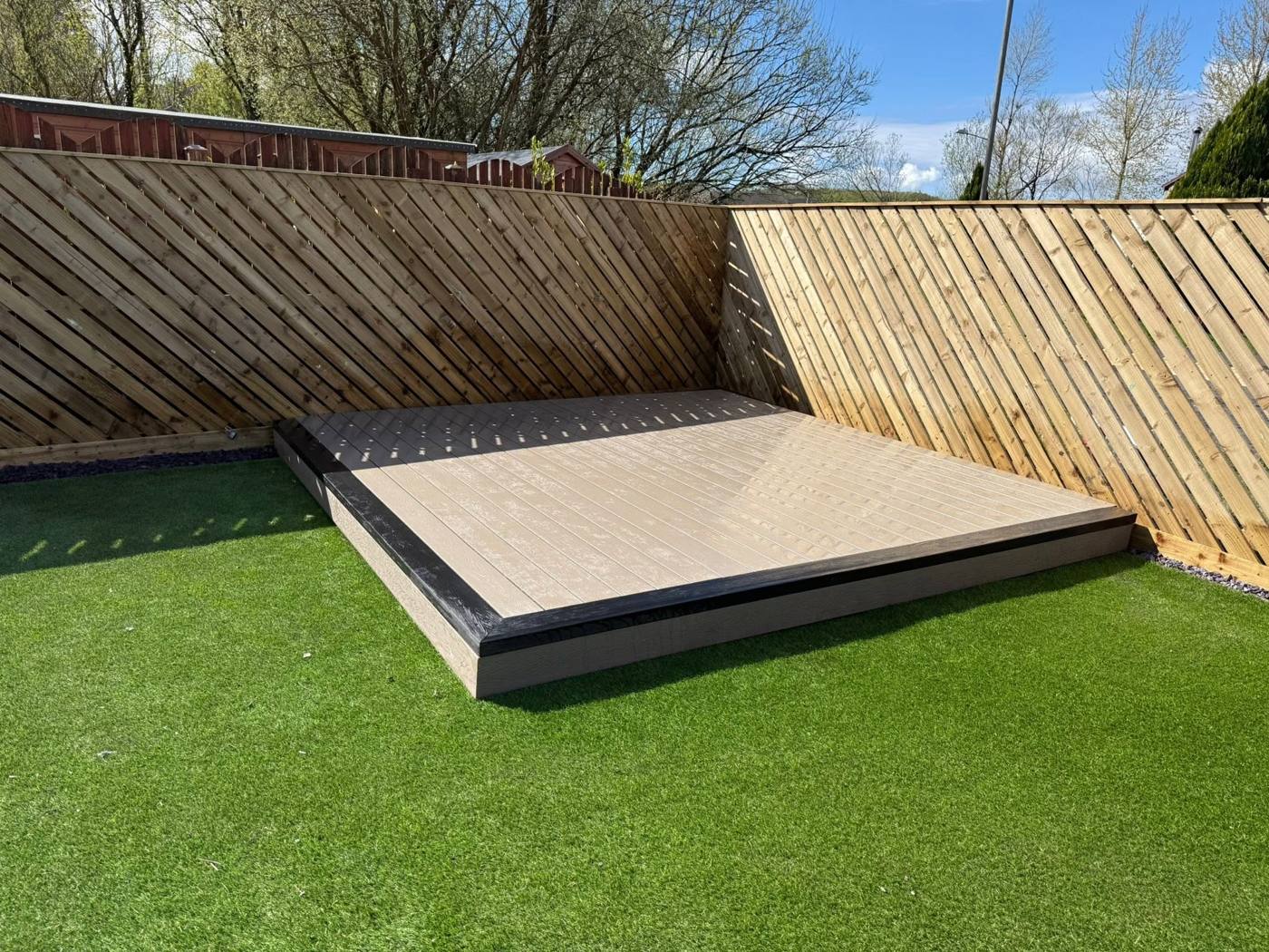 Composite decking with black edging and diagonal board fencing