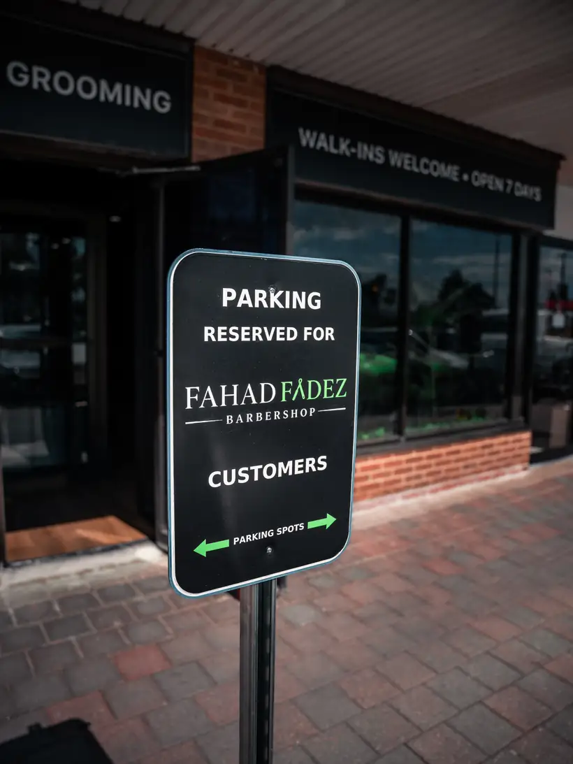 Sign outside the shop reading parking reserved for FahadFadez Barbershop customers