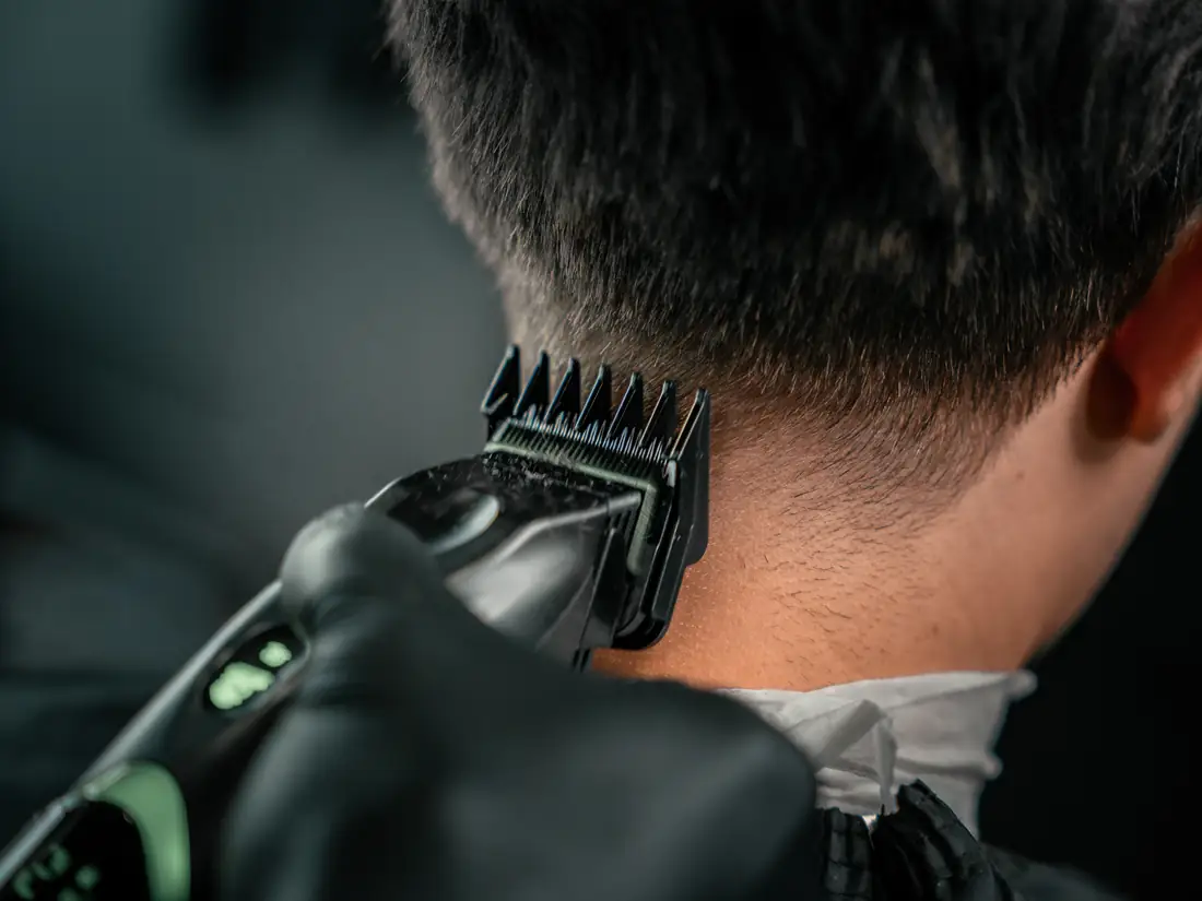 Clippers cleaning up the hairline at the back of a client&rsquo;s neck