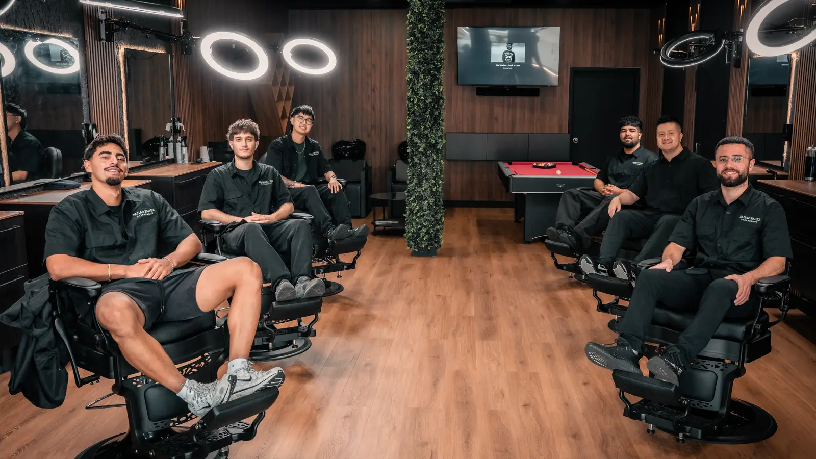 The barbers of FahadFadez Barbershop sitting in the chairs on the shop floor