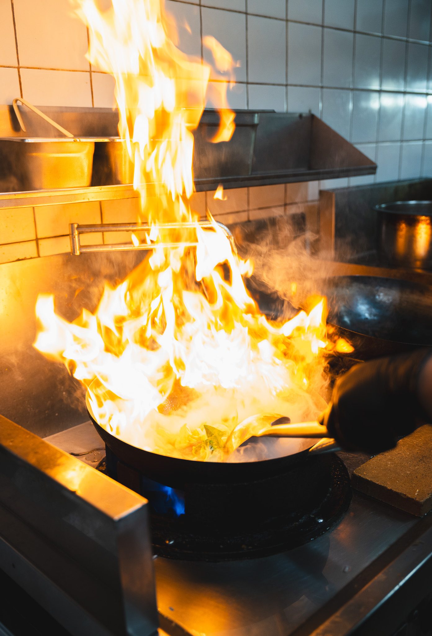 Flames leaping from a wok in the At Thai kitchen