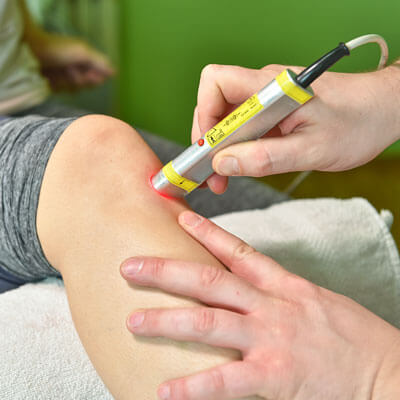 A doctor provides laser therapy for a patients leg.