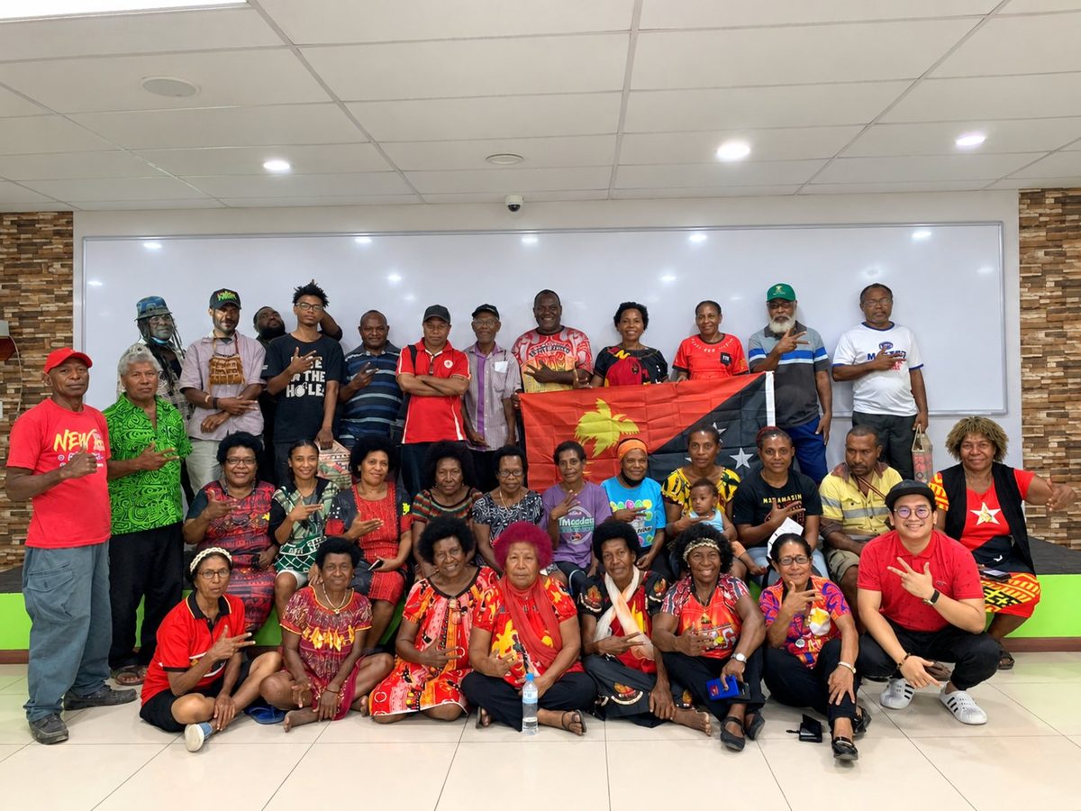A full room at an AI-Wealth X session, the Papua New Guinea flag held up in the middle of the group