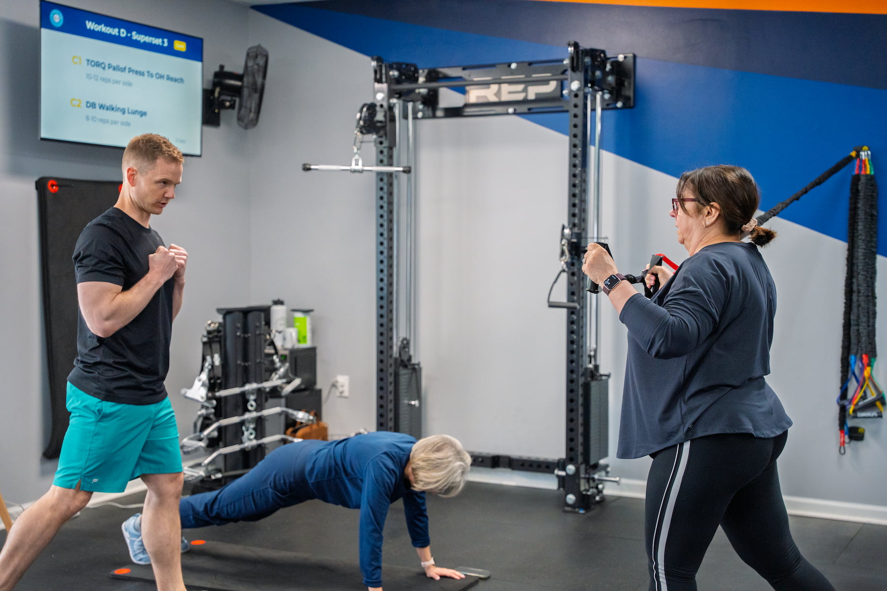 Corey coaching two Fitspire members through a plank and a band row