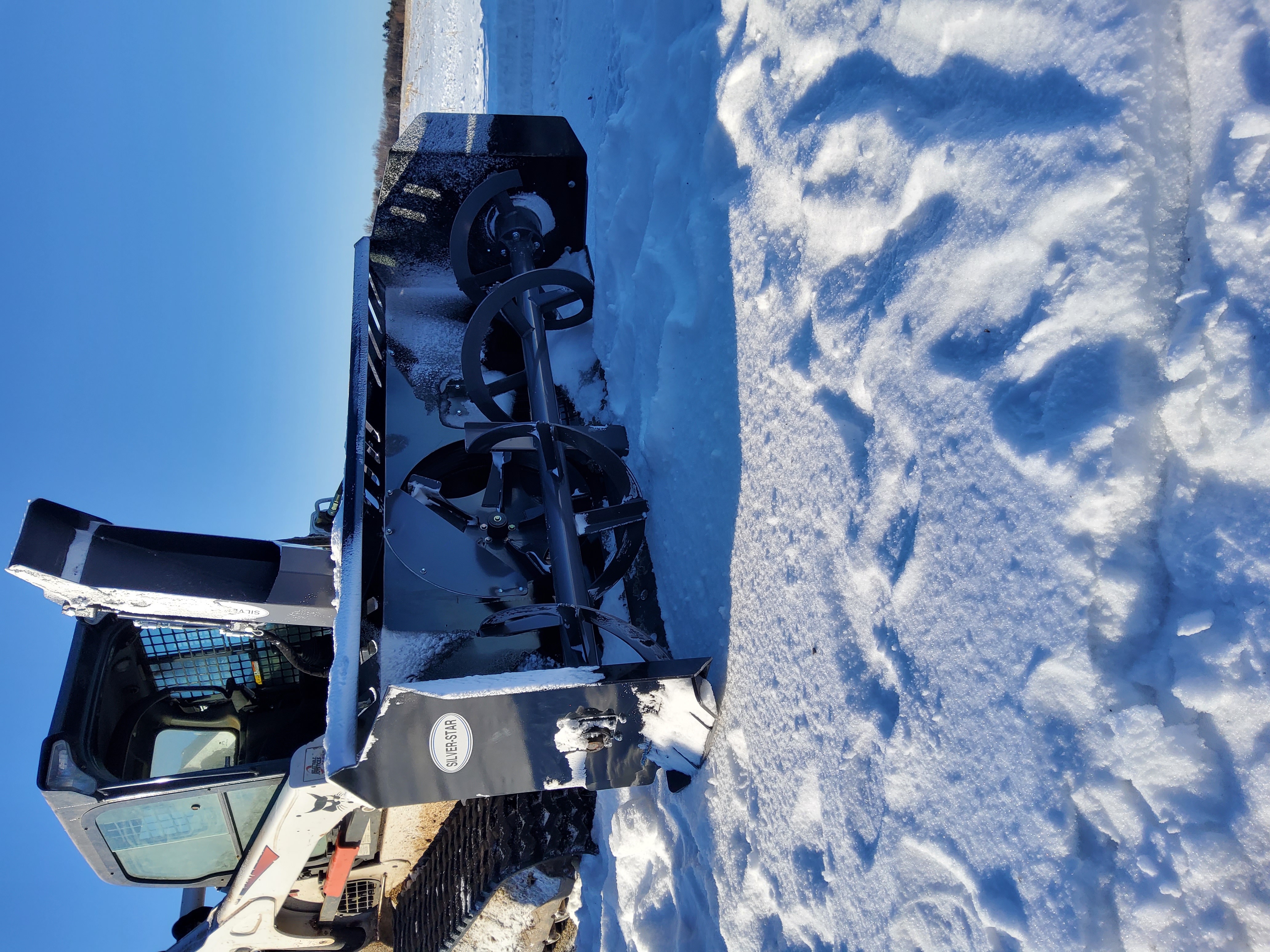 Compact skid steer loader with attachment clearing narrow urban alley Compact skid steer loader with attachment clearing narrow urban alley