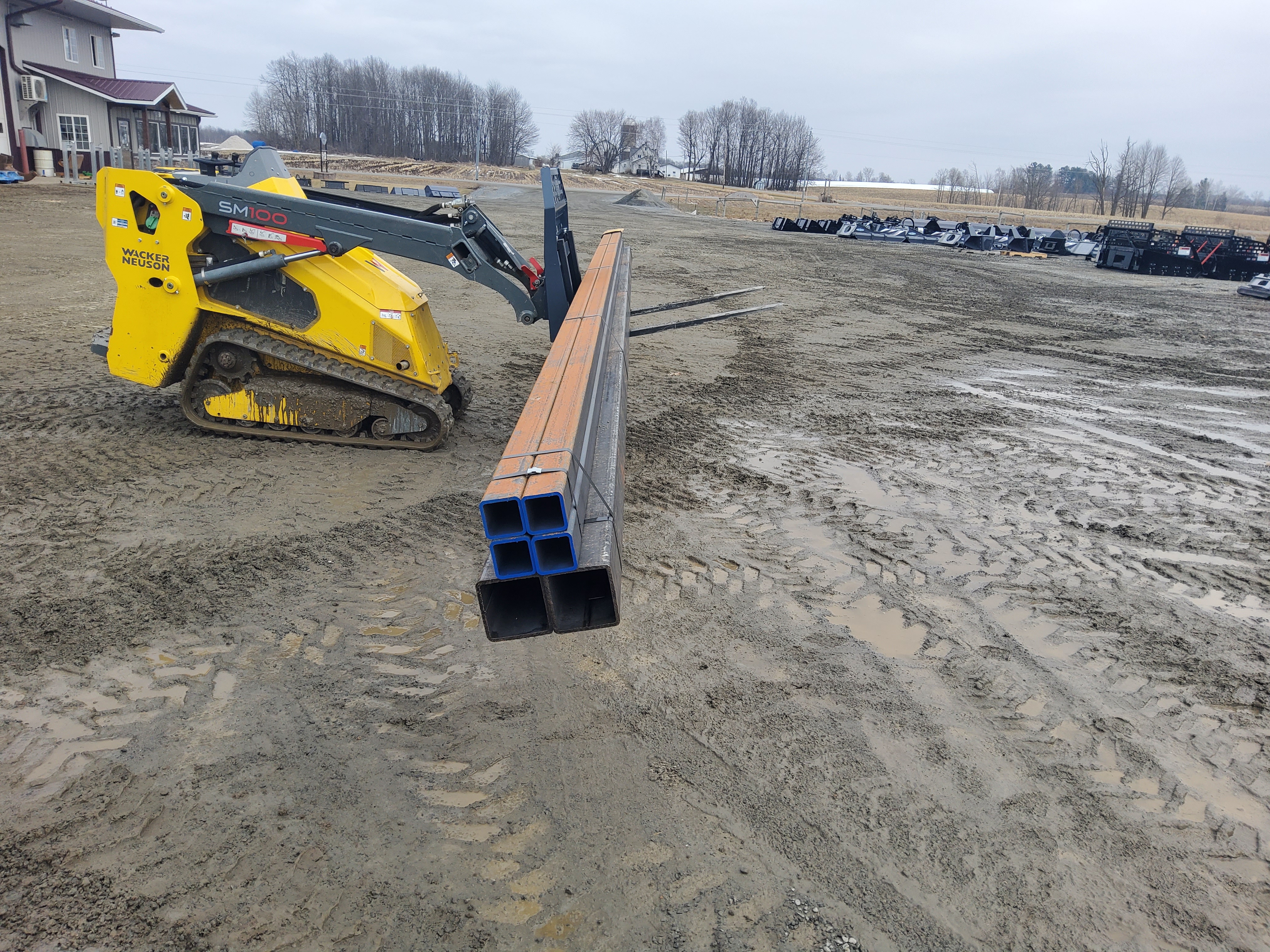 Mini skid steer with pallet forks working in residential landscaping setting Mini skid steer with pallet forks working in residential landscaping setting
