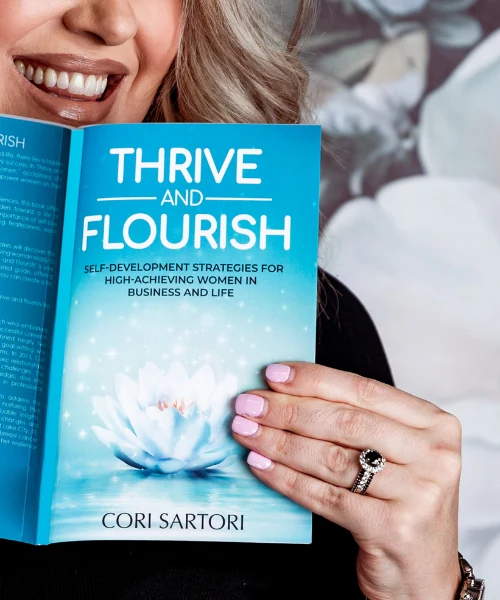 Cori Sartori holding her bestselling book Thrive and Flourish