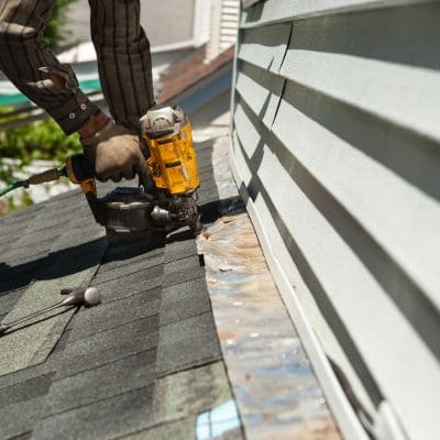 roofer securing the edge of a roof with a nail gun