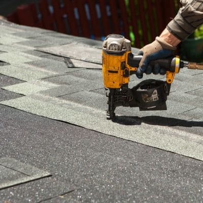 Contractor installing new roof shingles with precision