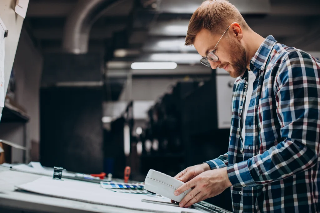 Print worker operating commercial printing press with paper and paints - TSG Group Hempstead NY