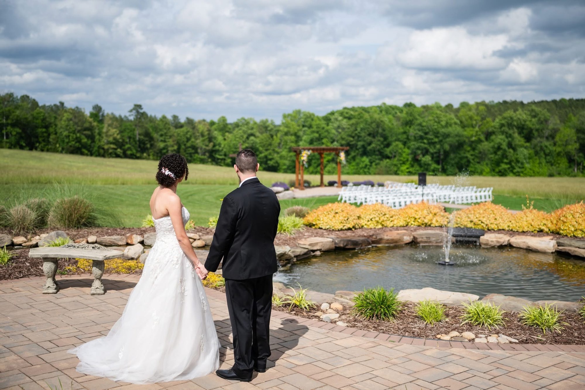 A couple looking out over the pond toward the ceremony arbor