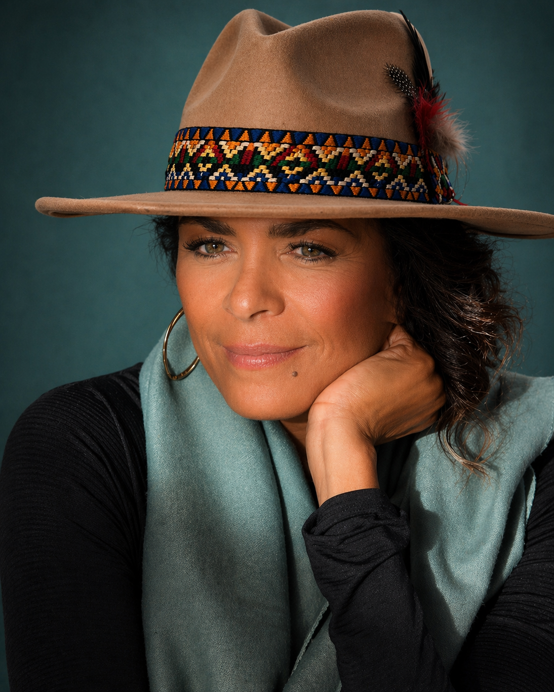 Reflective portrait of Darieth Chisolm wearing a patterned hat and blue scarf