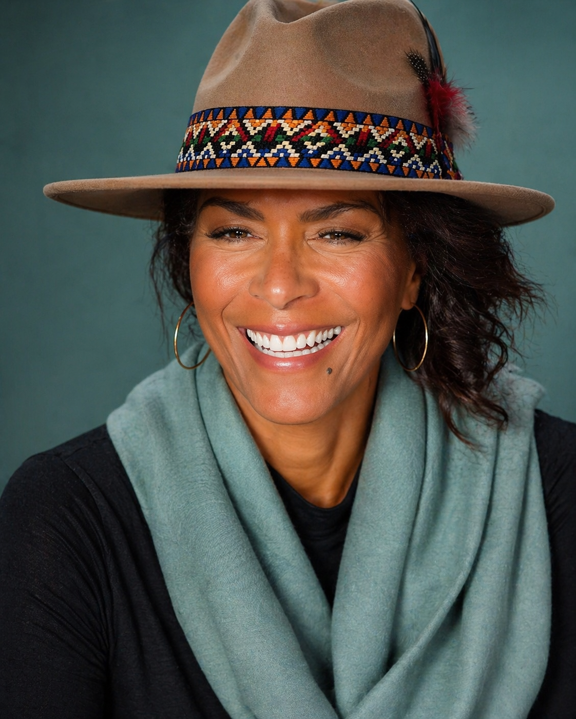 Darieth Chisolm smiling in a patterned hat and soft blue scarf