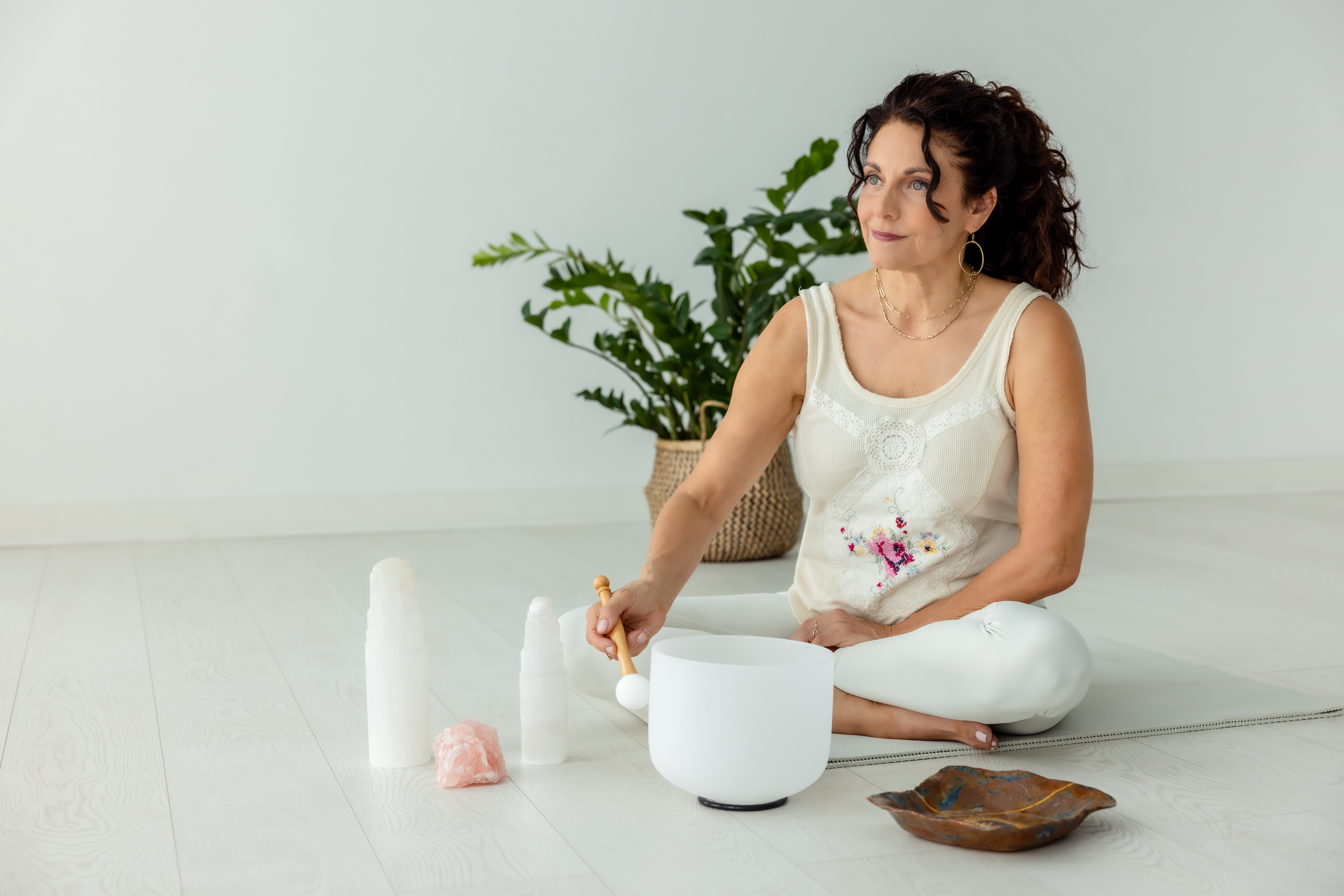 Kristina seated with a crystal singing bowl in a bright, calm studio