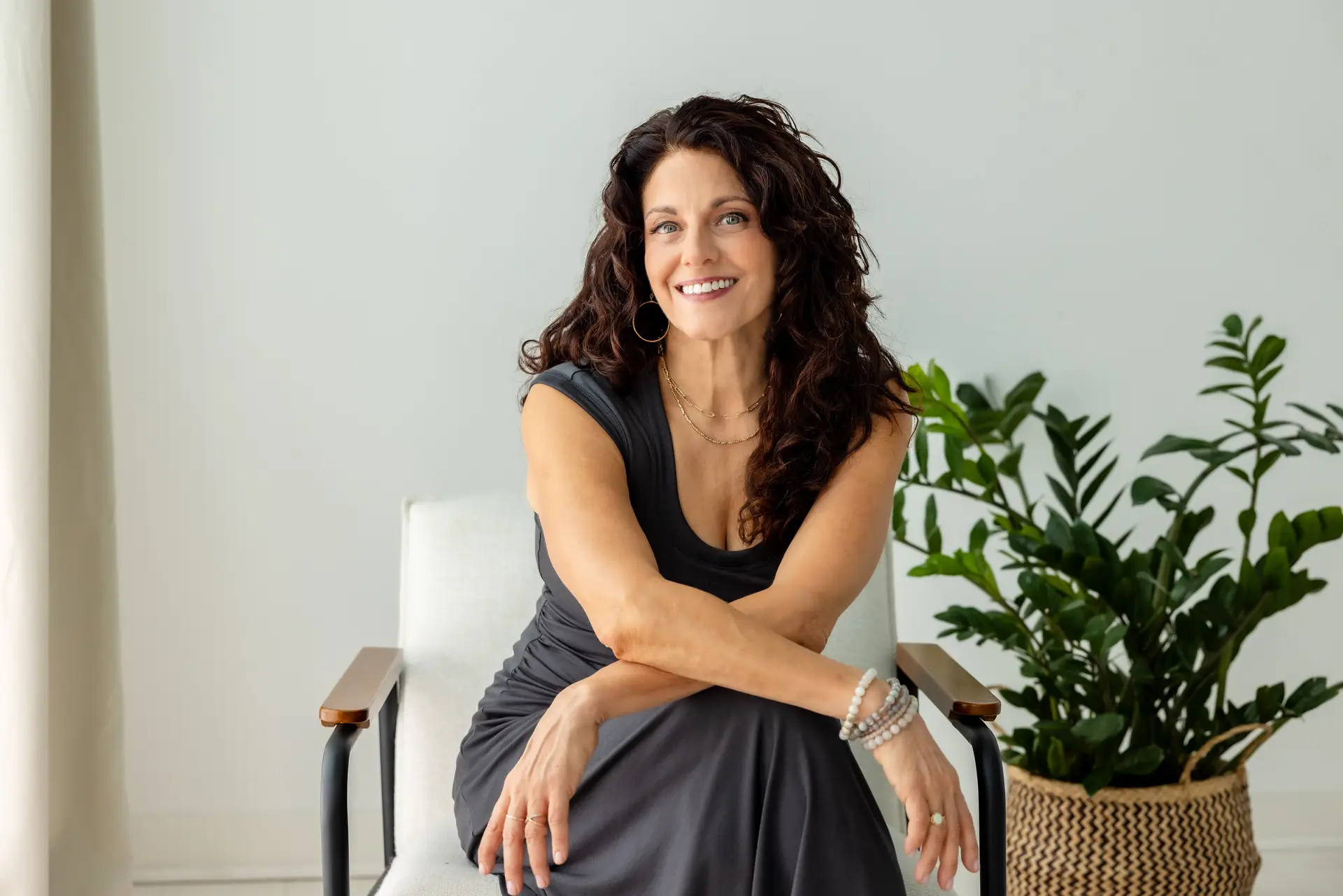 Kristina, seated and smiling, in a calm, light-filled studio
