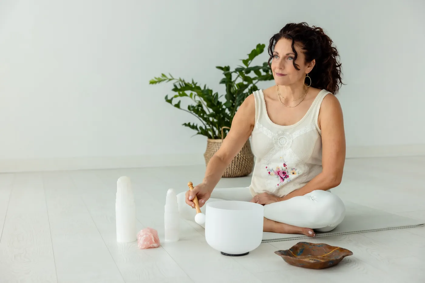 Kristina seated with a crystal singing bowl in a bright, calm studio