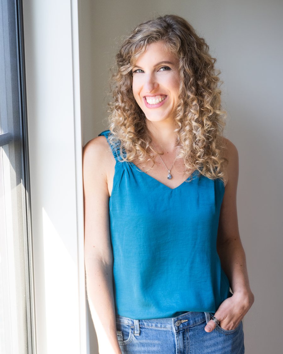 Dawn Apuan smiling by a window in a teal top