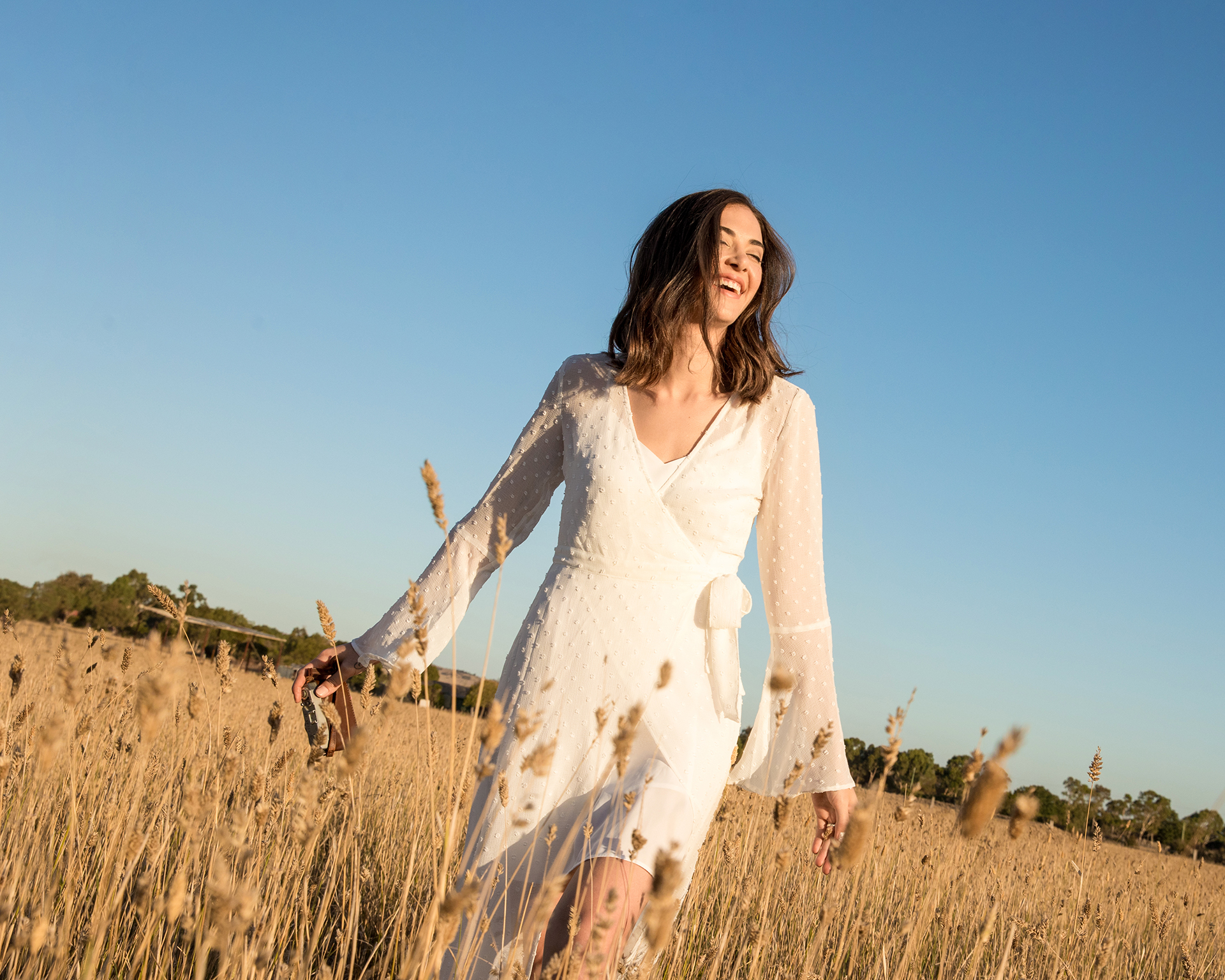 Lady walking through a golden field of long grass with blue sky Alison McWhirter Personal Branding Photography melbourne