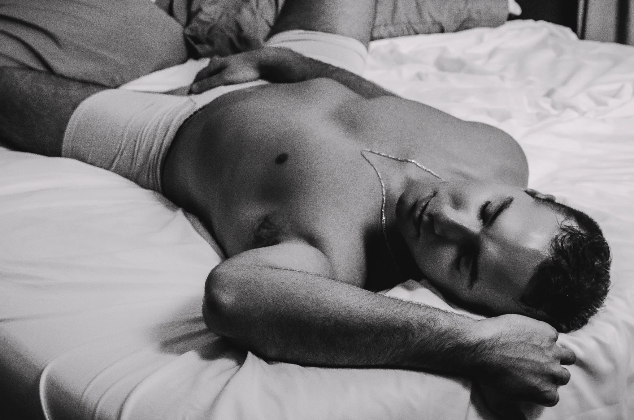 man lying on bed wearing boxer briefs