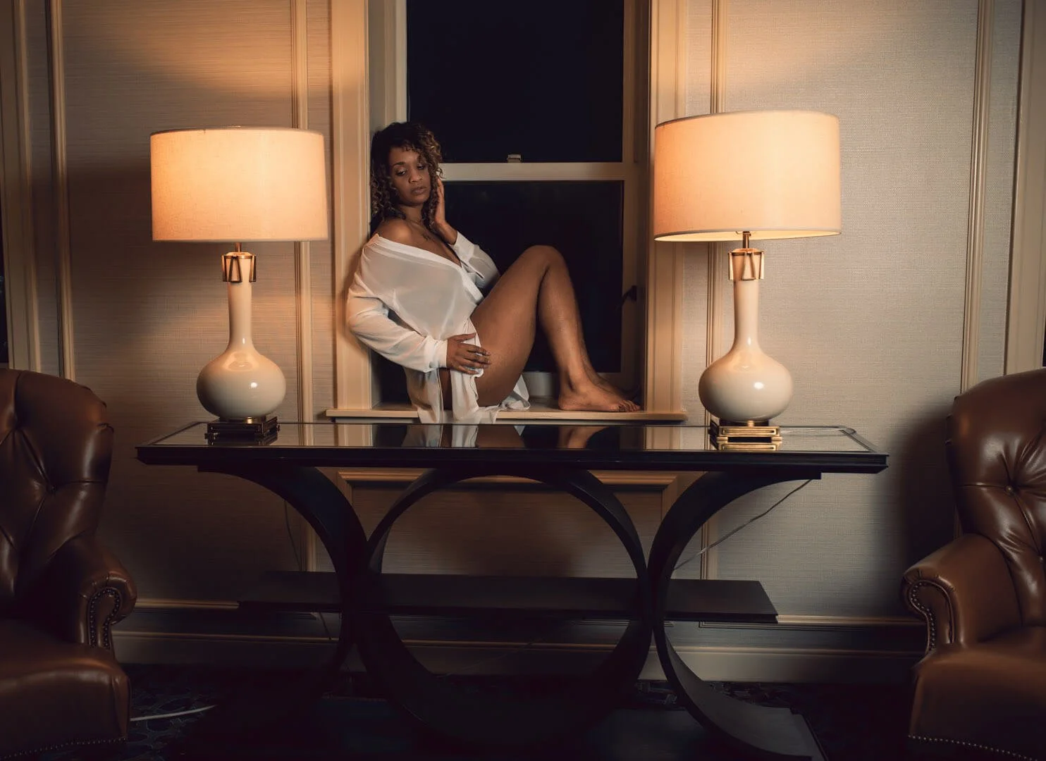 young woman sitting in window at night