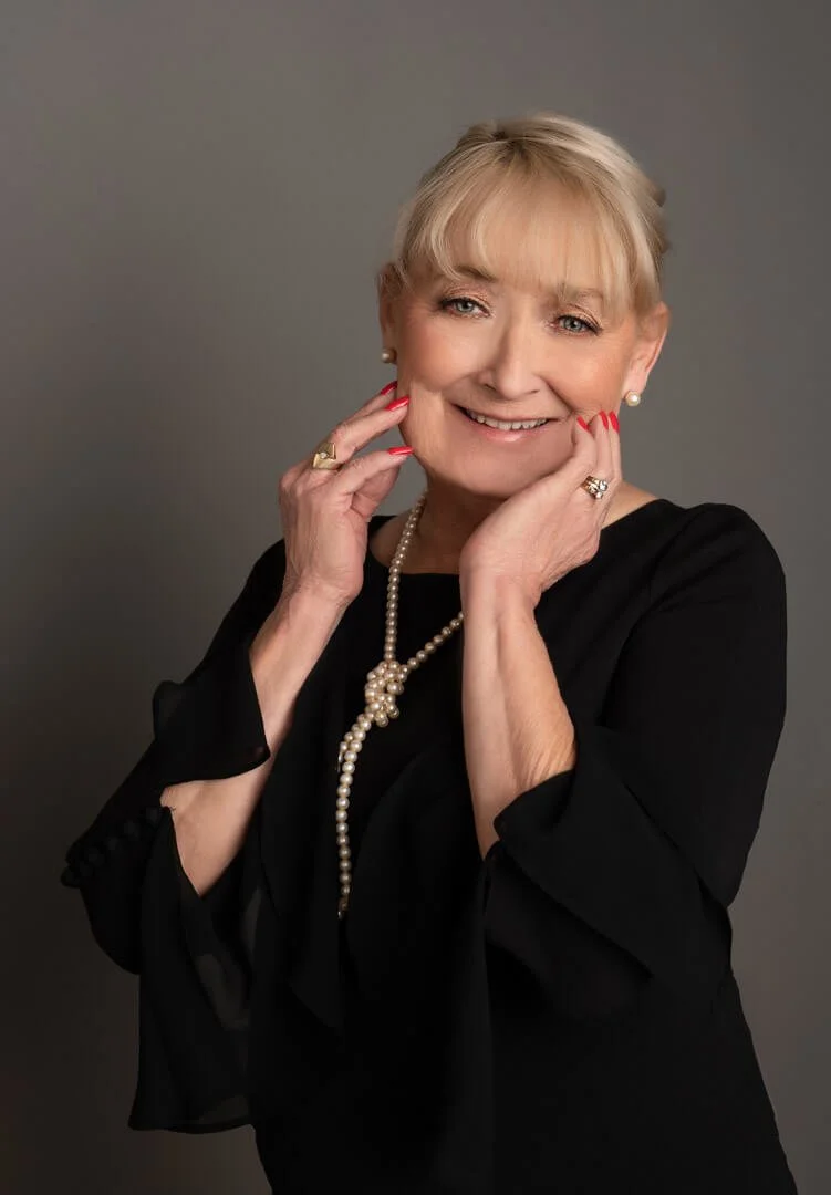 mature woman in black dress with pearls