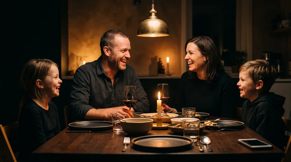 A contractor laughing at a candlelit family dinner with his phone face down