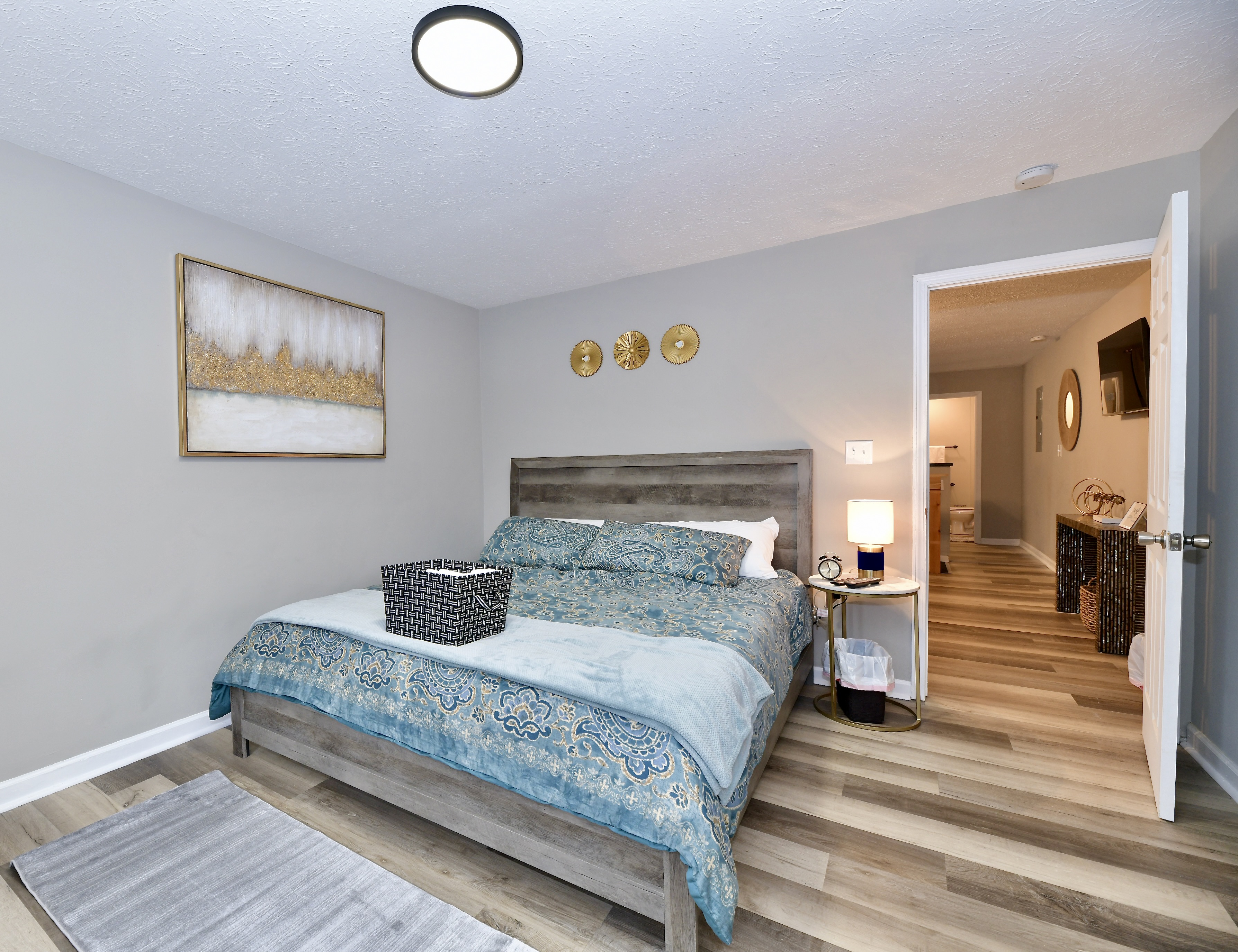 A furnished bedroom in a short-term rental property in Indianapolis, Indiana, styled with teal bedding, gold accents, and hardwood floors. A furnished bedroom in a short-term rental property in Indianapolis, Indiana, styled with teal bedding, gold accents, and hardwood floors.