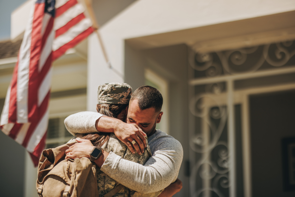 3:41 PMMilitary homecoming reunion, wife in uniform embracing husband in front of their home 3:41 PMMilitary homecoming reunion, wife in uniform embracing husband in front of their home
