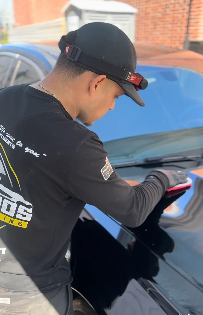 Joaquin from Los Primos providing a paint correction step using a clean cloth on the paint