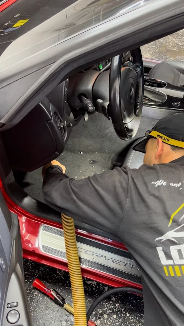 Joaquin from Los Primos Auto Detailing cleaning the carpets on an interior lean for a red corvette in san leadnro