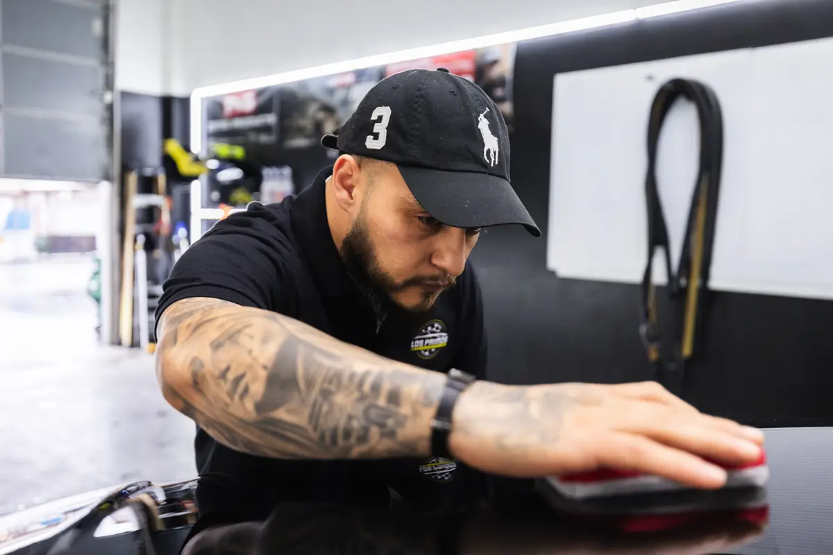 Joaquin from Los Primos providing a paint correction step using a clean cloth on the paint