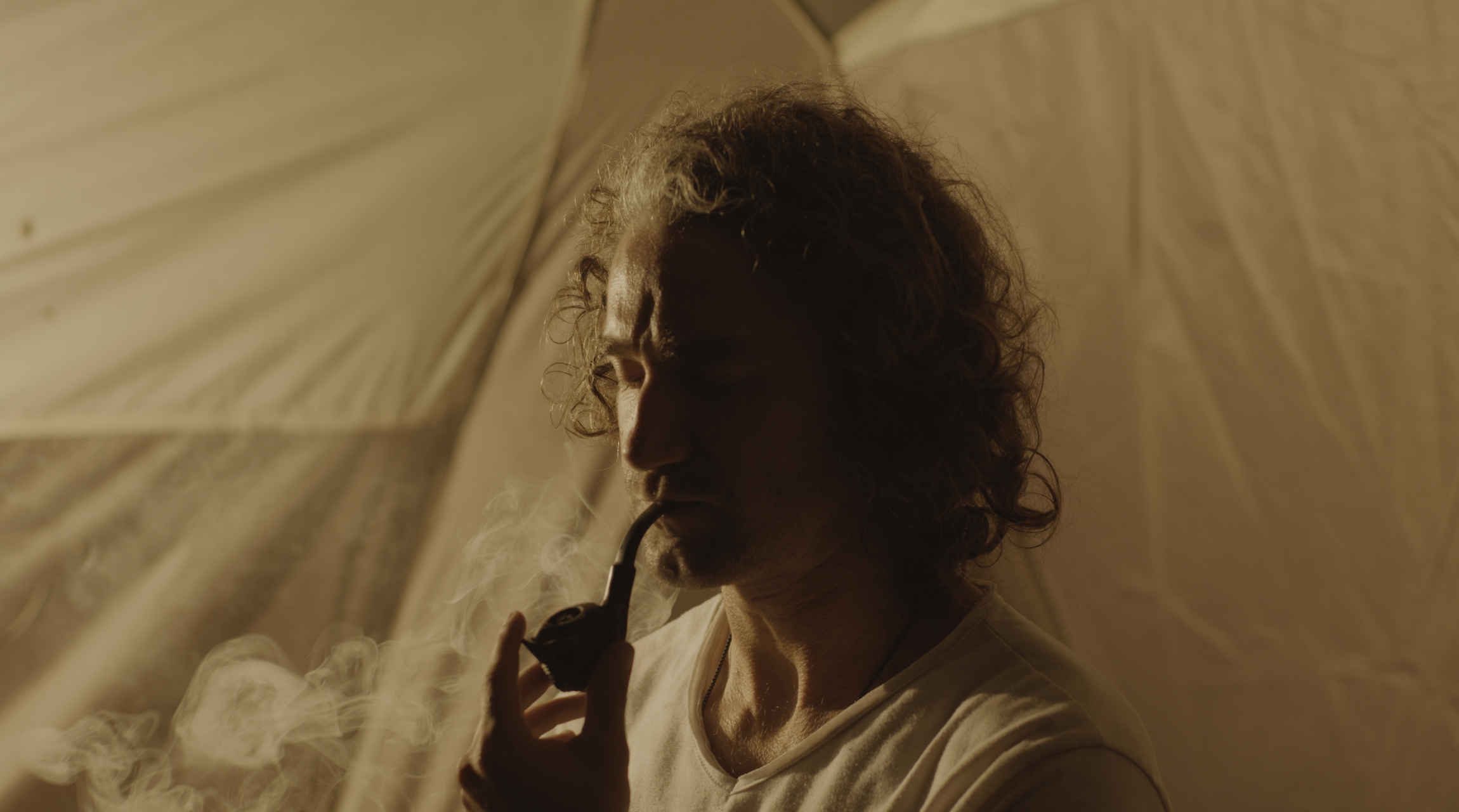 A practitioner smoking a pipe inside a ceremonial tent