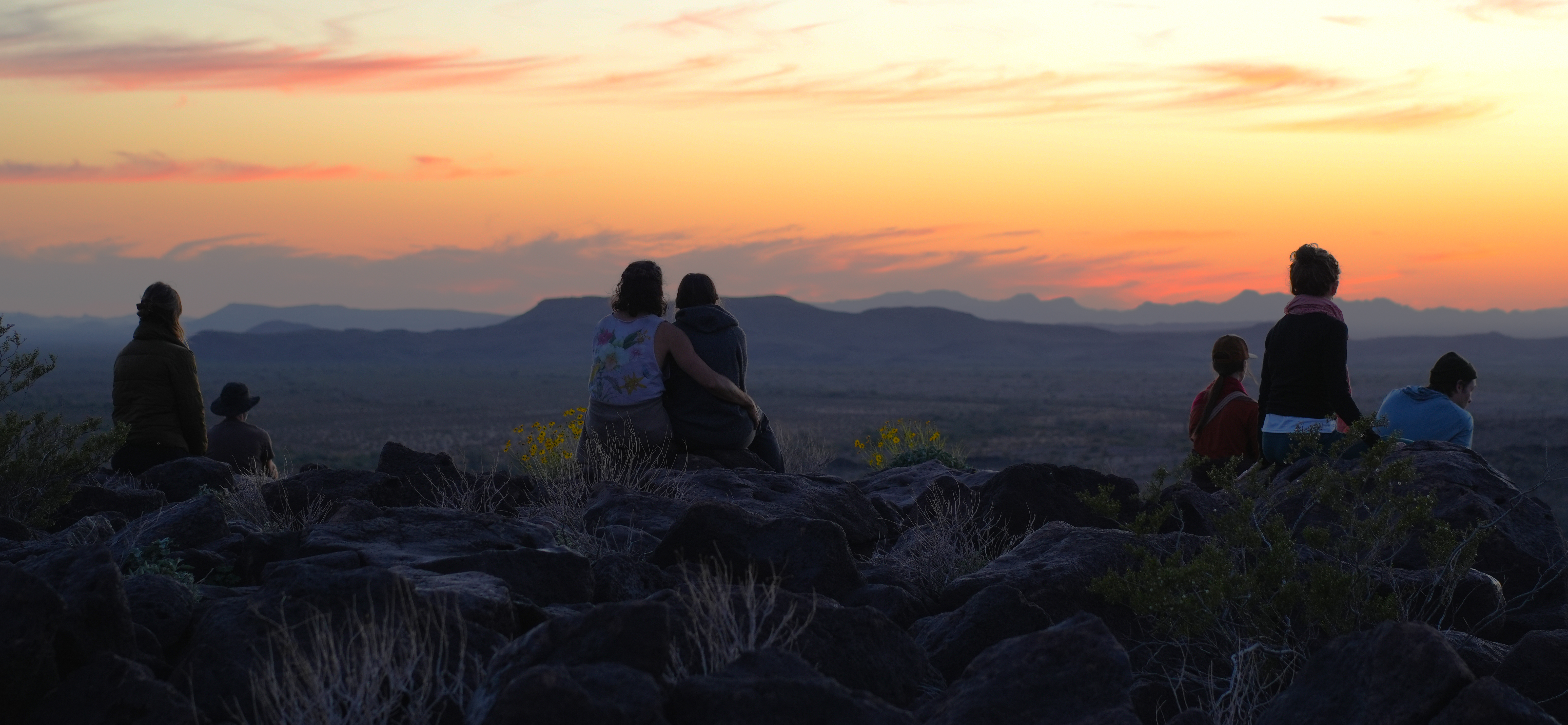 Participants together on a rocky desert hill at sunset