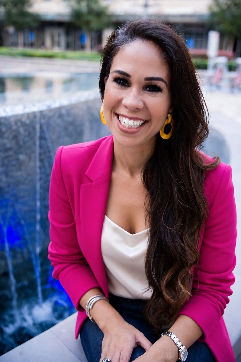 Cathy Christen smiling in a pink blazer beside a fountain