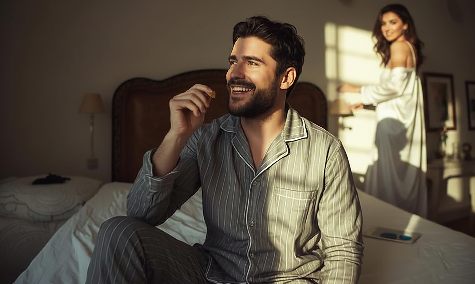 Man enjoying a BITCOLA QuickStart Gummie in a bedroom with his partner nearby