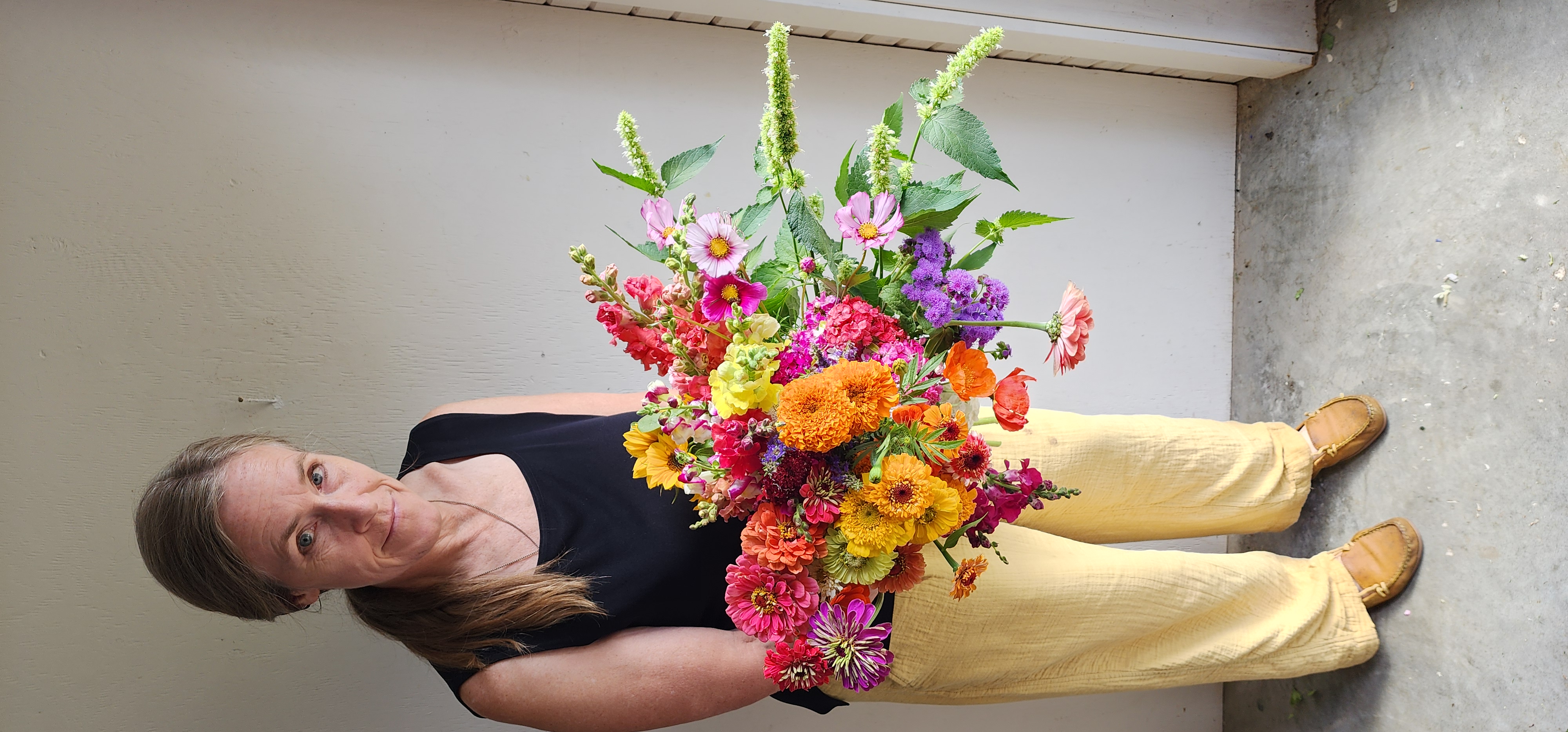 Paula holding a bucket of bright colorful flowers