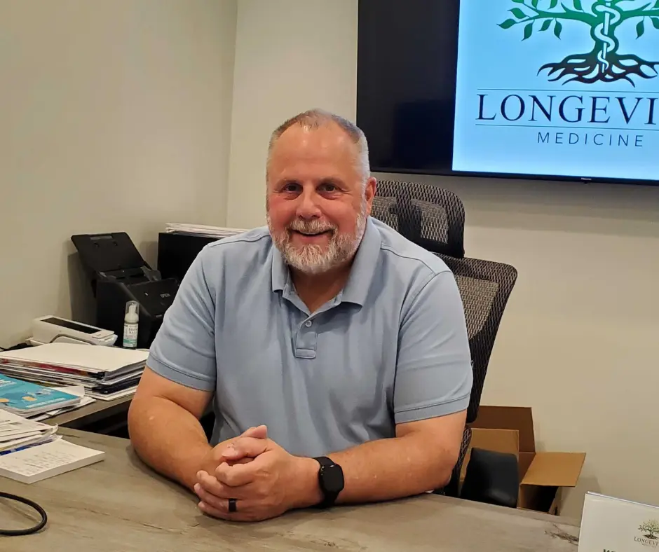 Dr. Brian Rodgers seated at his desk in the Longevity Medicine office
