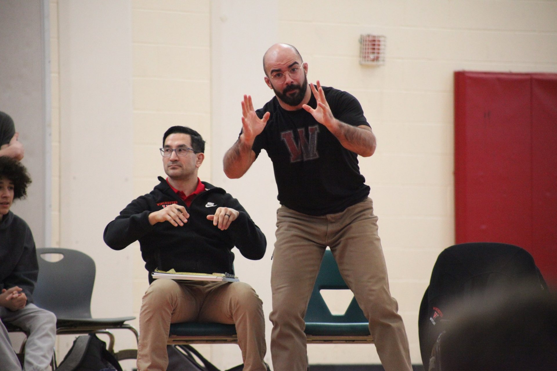 Winchester coaches cheering on a wrestler from their mat-side chairs