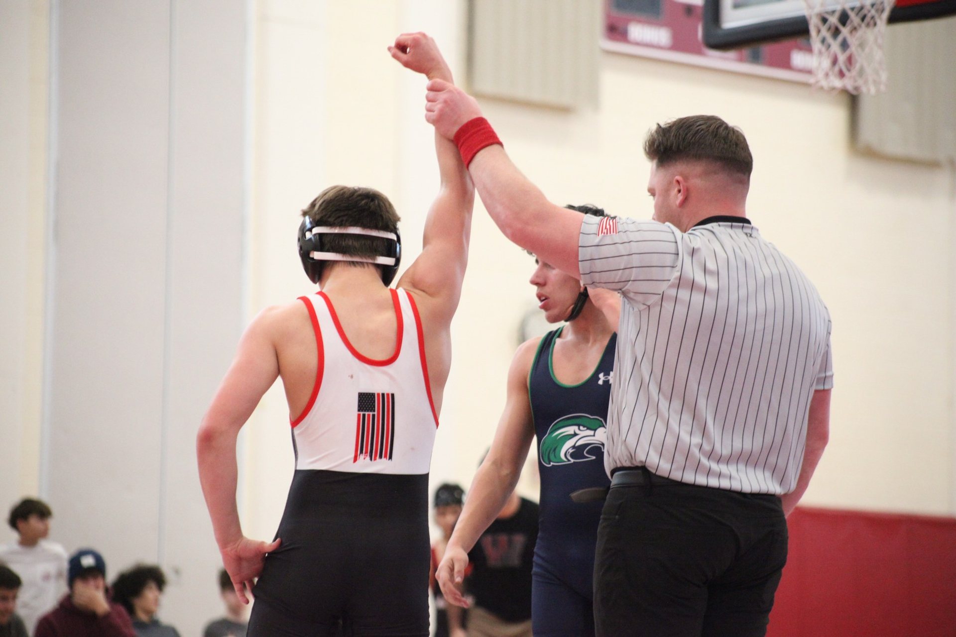 A referee raising the hand of a Winchester wrestler after a match