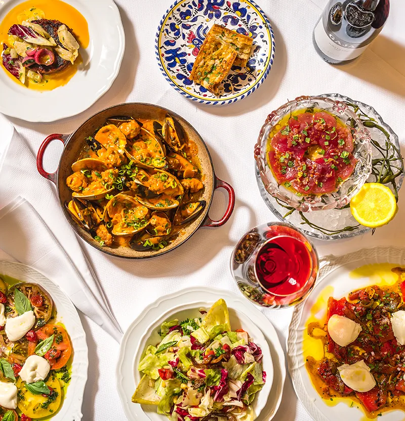 A table set with Italian dishes, wine and salads