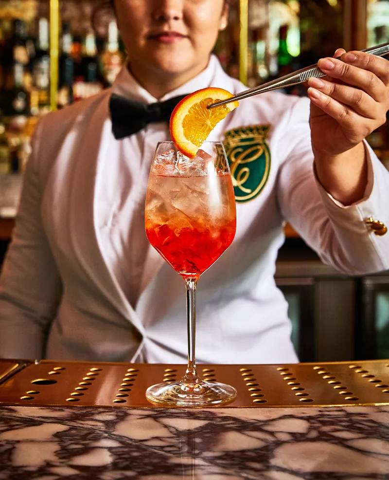 A bartender garnishing a spritz