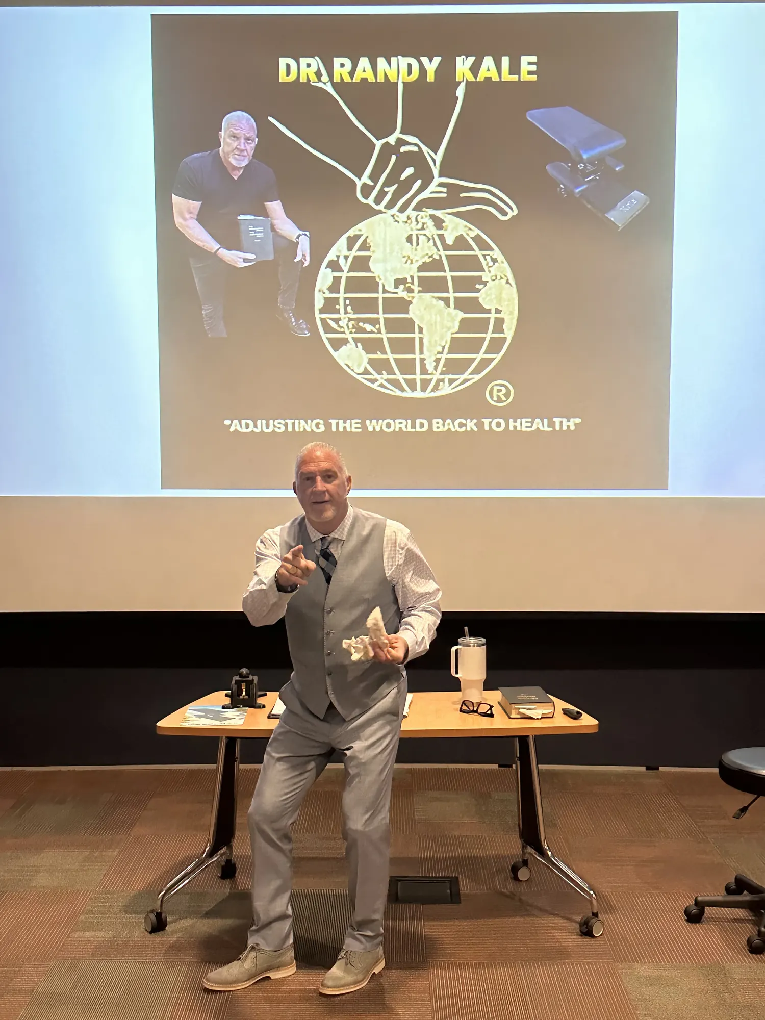 Dr. Randy Kale teaching doctors in front of his Adjusting the World Back to Health slide