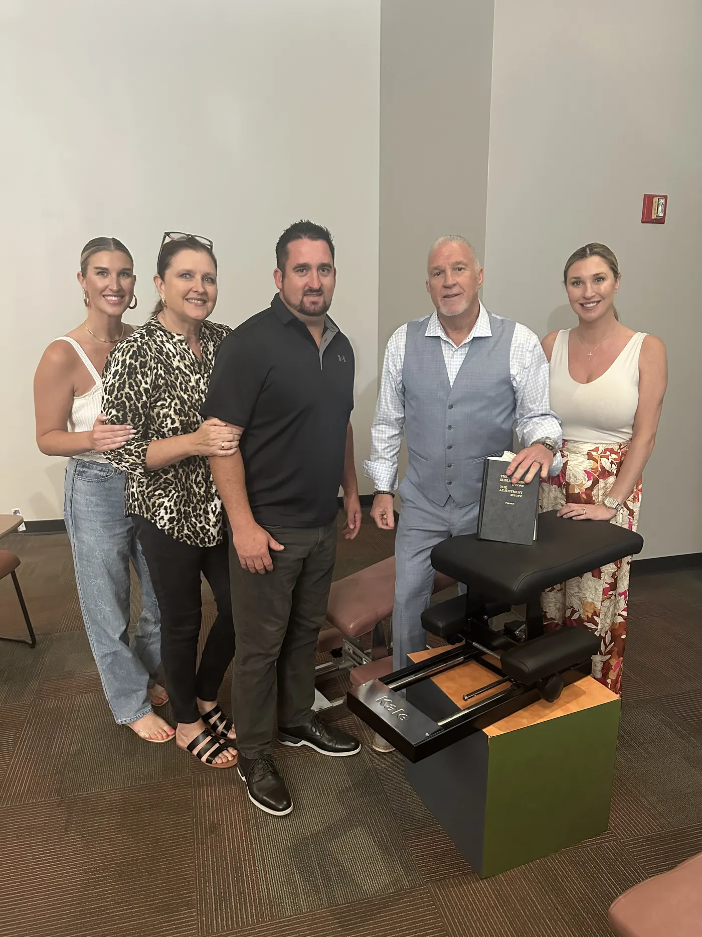 Dr. Randy Kale holding his book with four newly trained doctors beside a Kale knee chest table