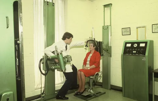 A vintage upper cervical x-ray room with a patient positioned in the chair