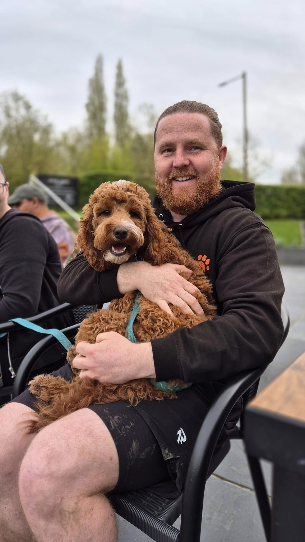 Adam smiling and holding a fluffy brown dog