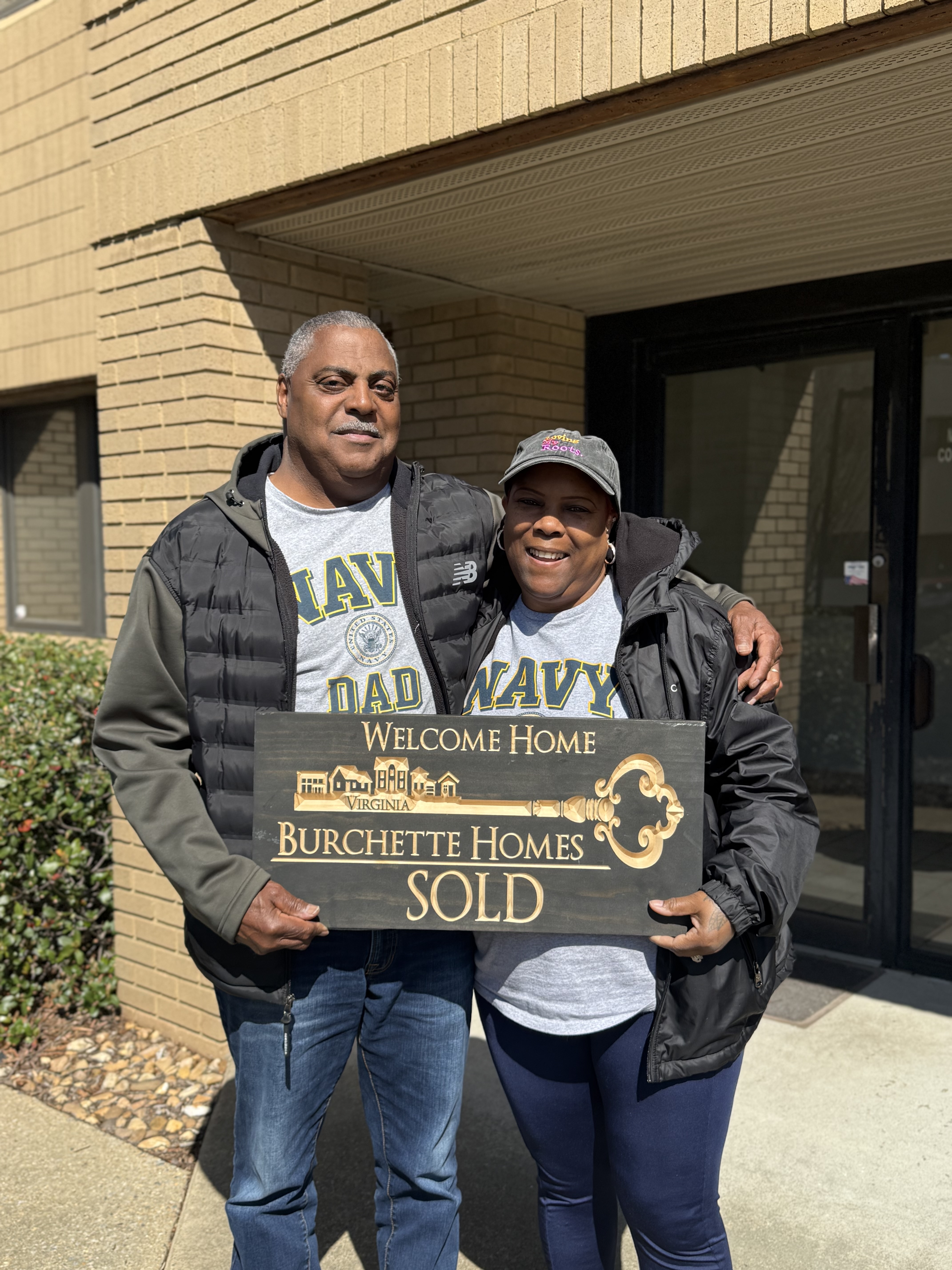Parents of a Burchette Homes client holding a sold sign while she was deployed